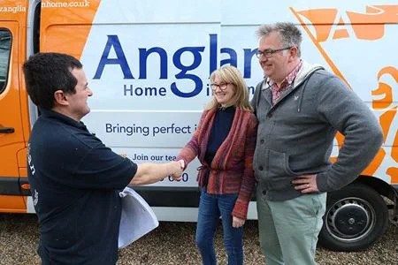 People shaking hands in front of van
